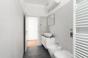 A modern bathroom with a toilet, bidet, and sink, marble walls, and a towel rack. - GuestHost - Cozy 55 sqm apartment, perfect for 3 people, located on the second floor of a building with an elevator (NOT accessible to disabled guests).The property is located in the Corvetto neighborhood, in a quiet residential area just steps from Vett (Milan)