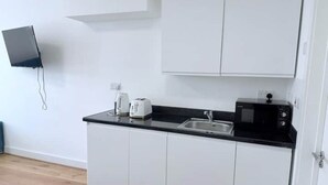 A modern kitchen with white cabinets, a black countertop, a microwave, and a toaster.