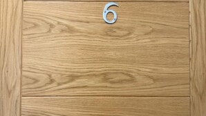 A wooden door with a metal number '6' sign.