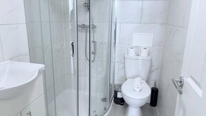A modern bathroom with a glass-enclosed shower, a white sink, and a toilet.