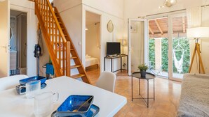 Uma sala de estar ampla com escada de madeira, televisão e varanda com vista.