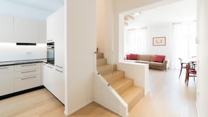 Een modern appartement met keuken, trap, zithoek met bank en eettafel.