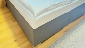 A modern bedroom with a grey bed, wooden headboard, and built-in wooden cabinets.