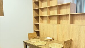 A wooden dining table with woven placemats, a basket, and a chair.