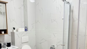 A modern bathroom with a toilet, sink, and shower.