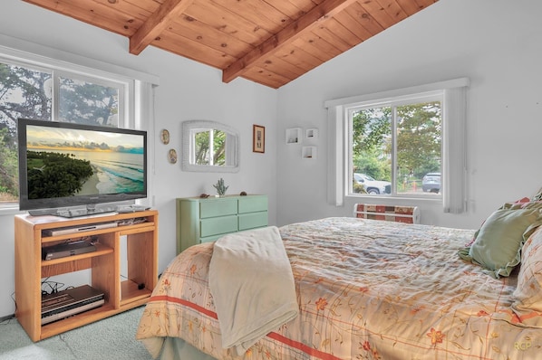 Une chambre à coucher comprenant un lit, une télévision, une commode et une fenêtre donnant sur l’extérieur.
