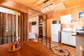 Interior em madeira com mesa de jantar, cadeiras, cozinha e cama.