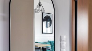 Un interno moderno con una porta in legno, un divano verde acqua, un tavolino e una lampada a sospensione.