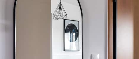 A modern interior with a wooden door, a teal sofa, a small table, and a hanging light fixture.