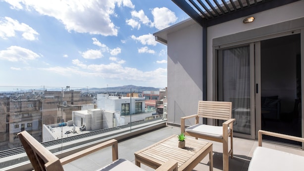 Un balcone con vista sulla città, arredi in legno e una porta finestra.