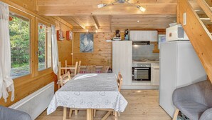 Ein Holzblockhaus-Interieur mit Essbereich, Küche und einer Schlafgalerie.