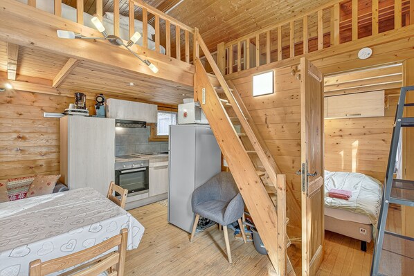 L’intérieur d’une cabane en bois comprend une cuisine, un coin repas et une chambre à coucher située en mezzanine.