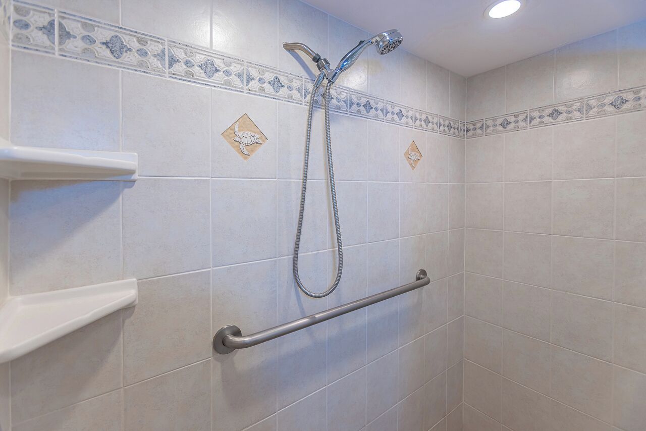 A shower with a handheld showerhead and a handheld shower attachment.