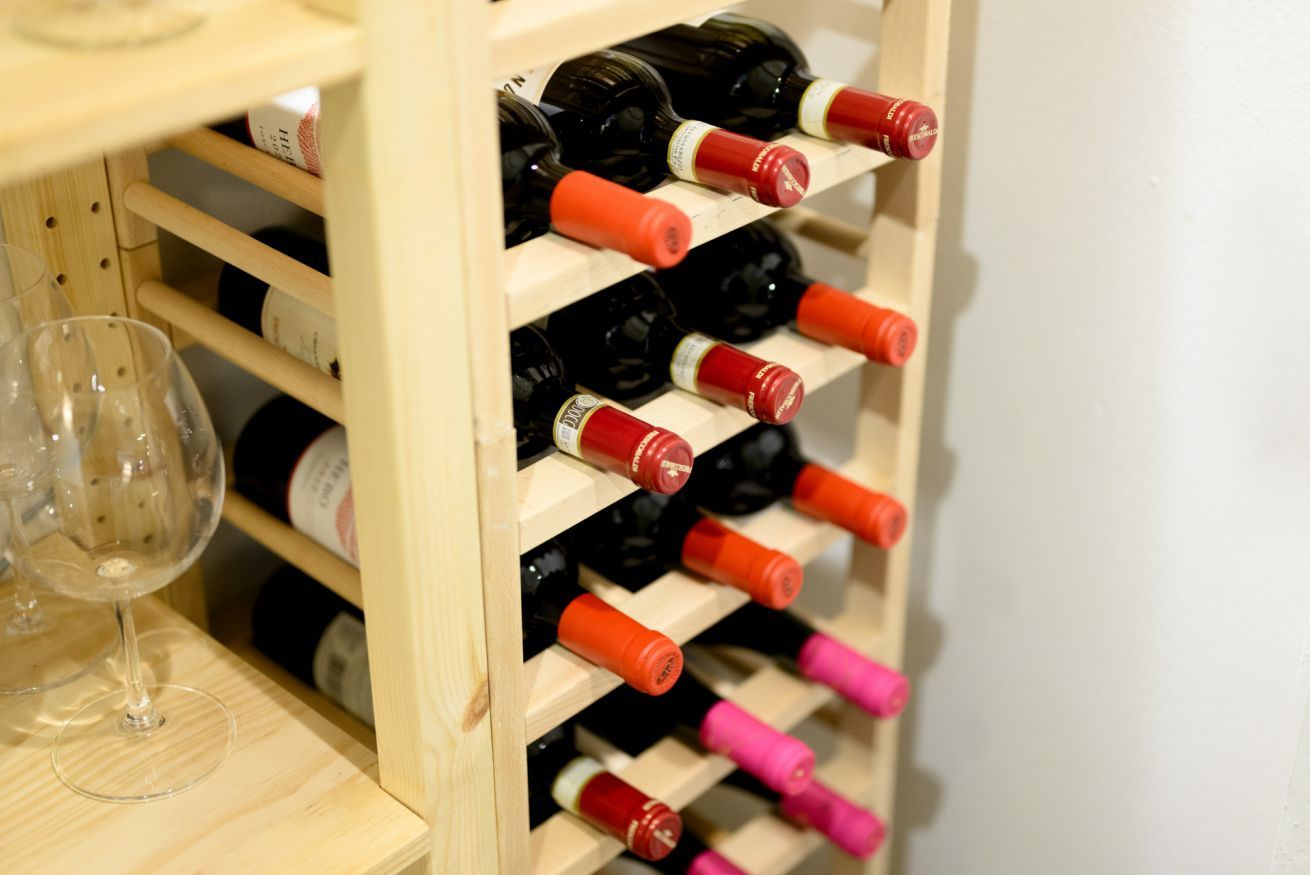 A wooden wine rack with multiple bottles and glasses.