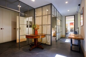 A modern interior with a round wooden table, a glass partition, and a view into another room.