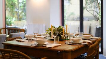 Une table à manger dressée avec des assiettes, des verres et des bougies, donnant sur un paysage verdoyant.