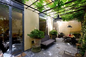 A covered patio with a glass door, outdoor seating, and potted plants. - Duomo Luxury Apartment with plunge pool (Firenze)