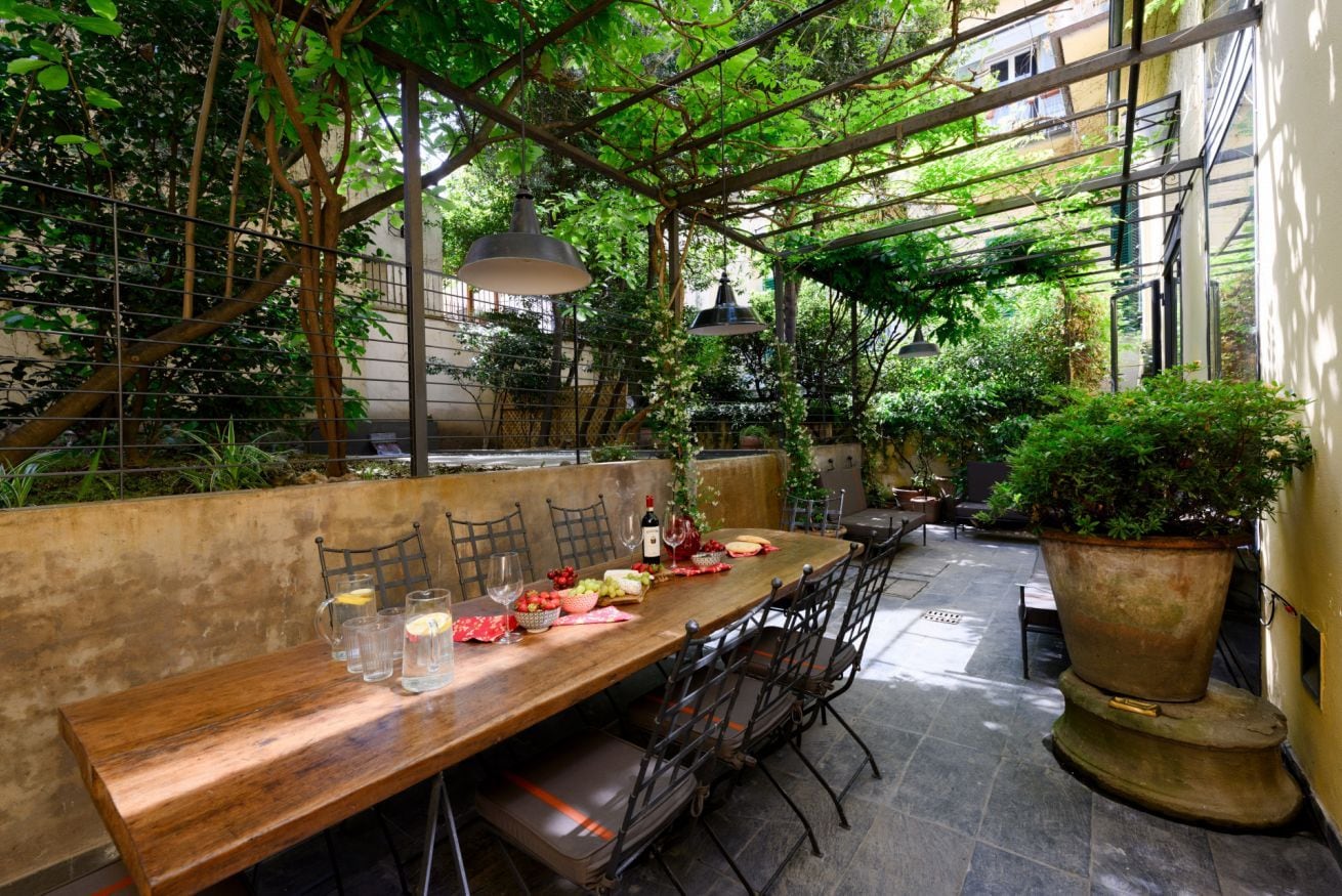 Un espace de restauration en plein air avec une longue table en bois, des chaises et un grand bac à plantes.