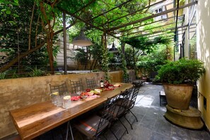 An outdoor dining area with a long wooden table, chairs, and a large planter. - Duomo Luxury Apartment with plunge pool (Firenze)