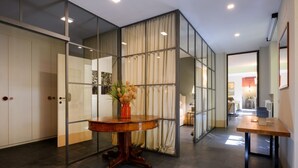 Een modern interieur met een ronde houten tafel, een glazen scheidingswand en uitzicht op een andere kamer.