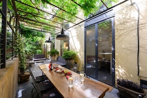 A covered patio with a wooden table set for dining, surrounded by potted plants and chairs. - Duomo Luxury Apartment with plunge pool (Firenze)