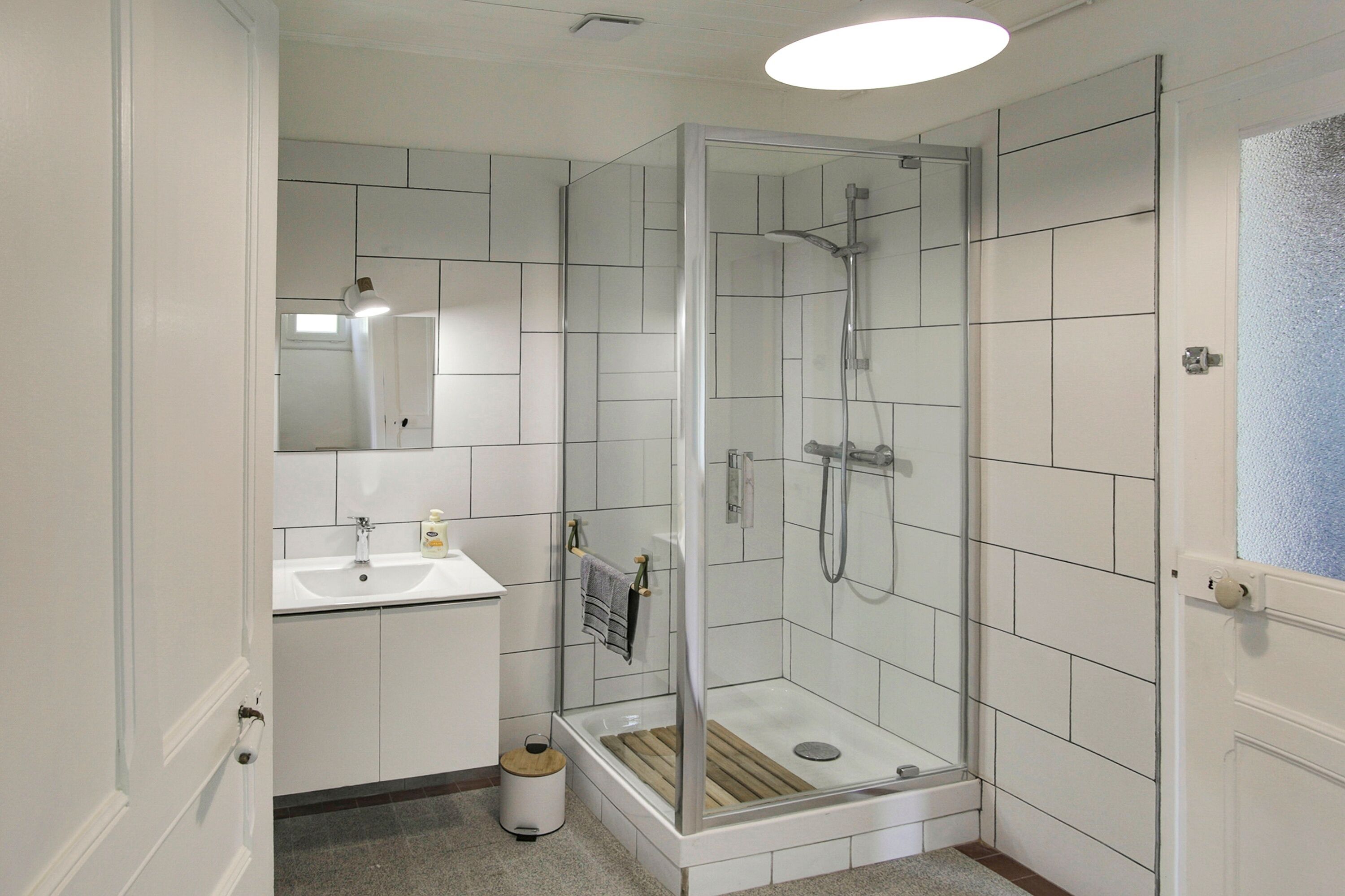 A modern bathroom with a glass-enclosed shower, a sink, and a mirror.