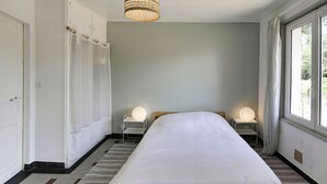 Ein Hotelzimmer mit einem großen Bett, zwei Nachttischen mit Lampen, einem Kleiderschrank und einem Fenster mit Vorhängen.