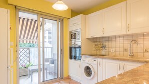 Une cuisine avec des meubles blancs, un four à micro-ondes, un lave-linge et un évier.