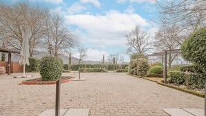 Ein gepflasterter Innenhof mit einer Pergola, Topfpflanzen und einem Holzzaun.