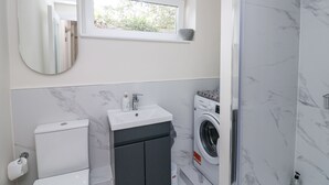 Une salle de bain moderne équipée de toilettes, d’un lavabo et d’un lave-linge.