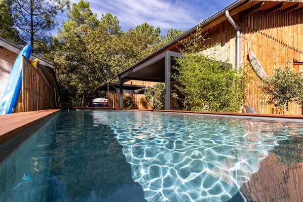 A swimming pool with clear water, surrounded by wooden fences and trees.
