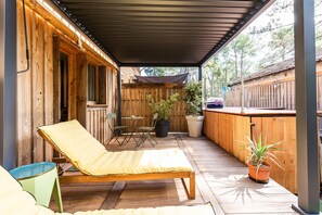 A wooden deck with a lounge chair, a small table, and potted plants.