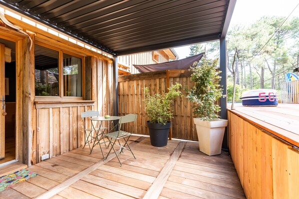 Une terrasse en bois dotée d’un espace abrité, d’un comptoir de bar et de plantes en pot.