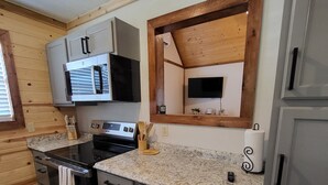 A compact kitchen with a built-in oven, microwave, and a small window above the sink. - Cozy Lakefront 2-bedroom cabin in tranquil Big Sandy, TX. (Big Sandy)
