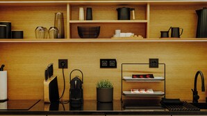 A modern kitchen with wooden shelves, a coffee machine, and a black sink.