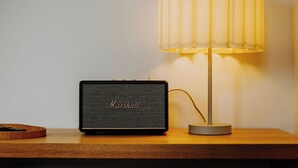 A black Marshall speaker and a lamp on a wooden surface.