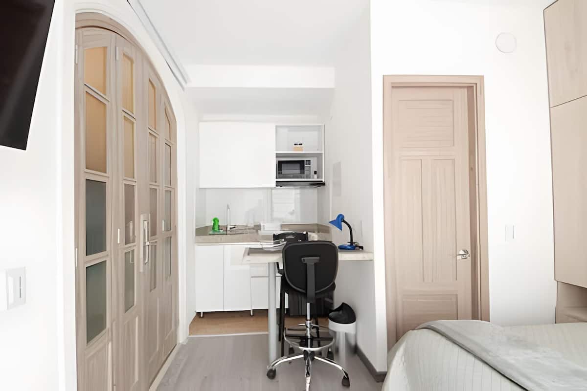 A compact kitchen with a microwave, a small dining table, and a chair.