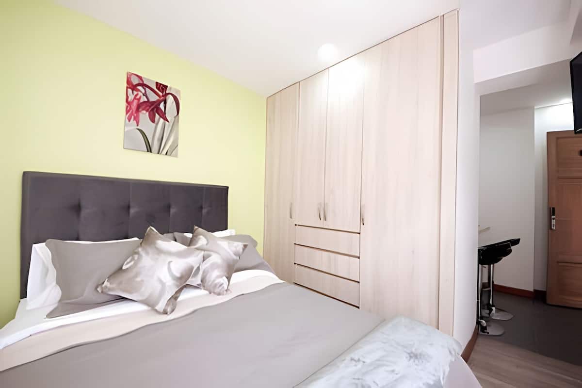 A bedroom with a bed, a wardrobe, and a painting on the wall.