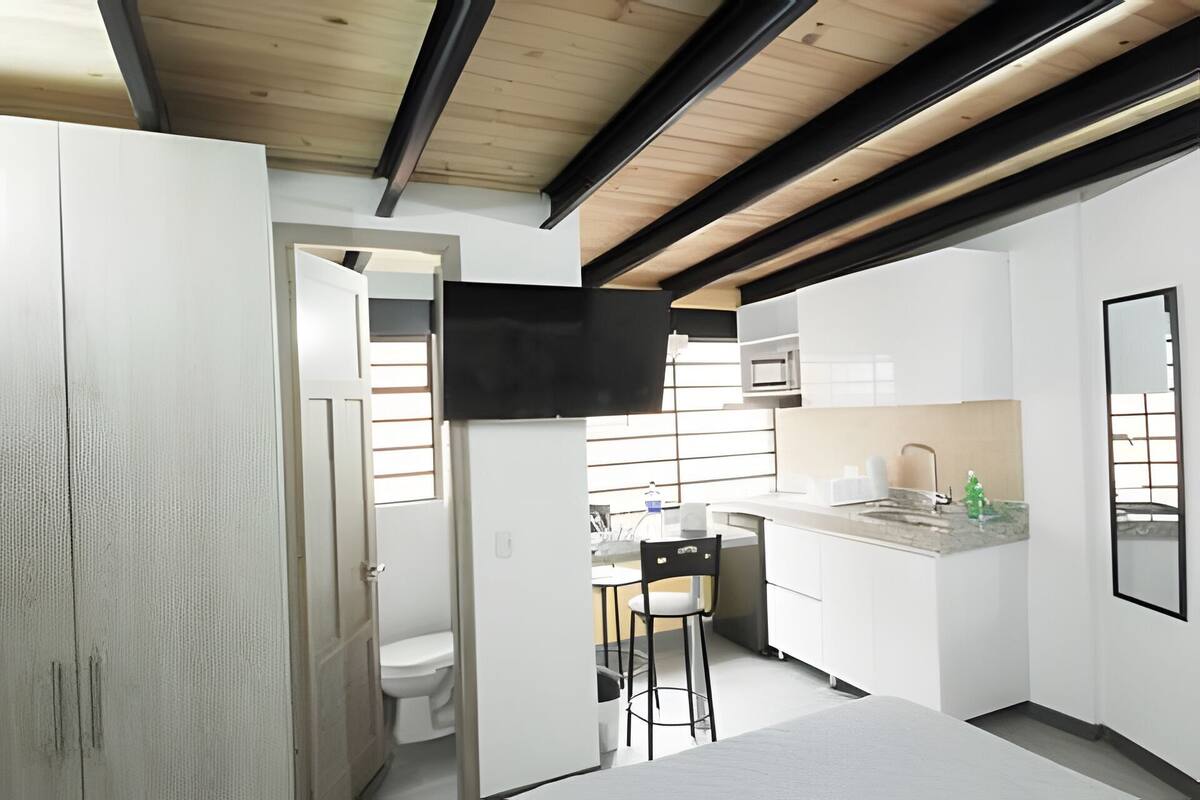 A modern kitchen with white cabinets, a built-in microwave, and a small island with bar stools.