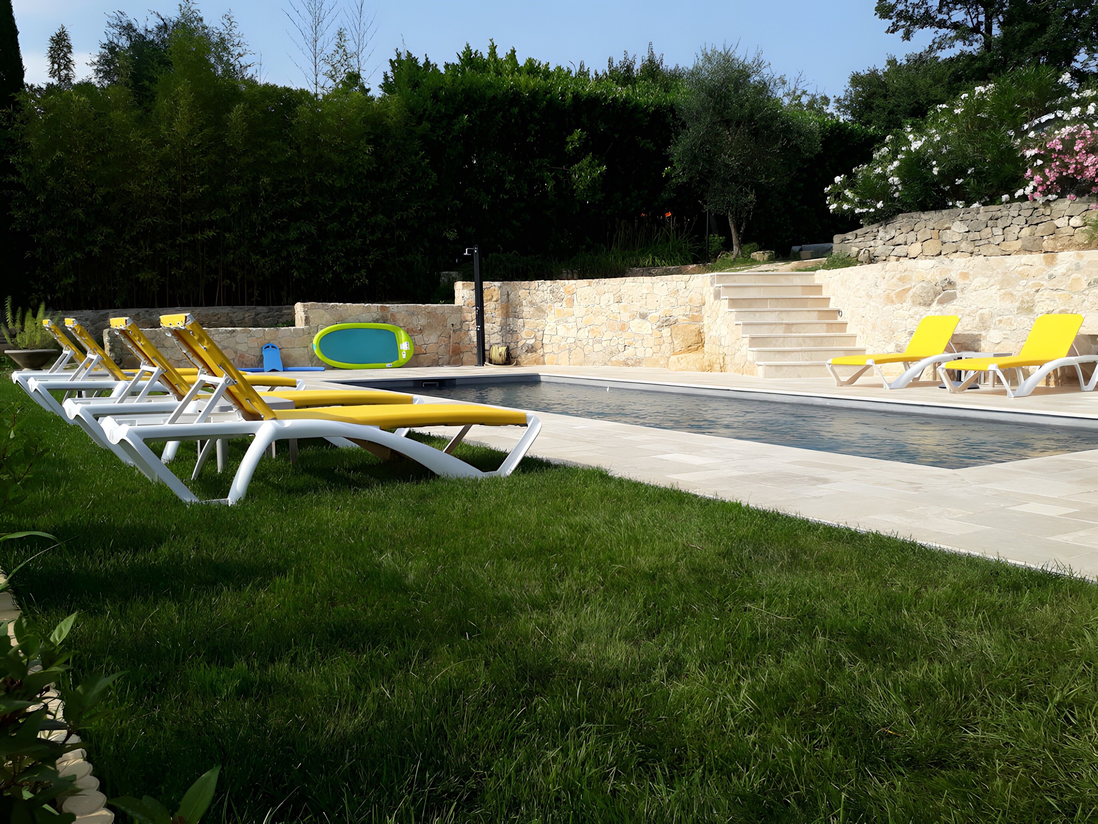 Ein Poolbereich mit Liegestühlen und einer Steinmauer.