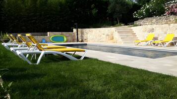 Ein Poolbereich mit Liegestühlen und einer Steinmauer.