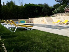 A poolside area with lounge chairs and a stone wall.