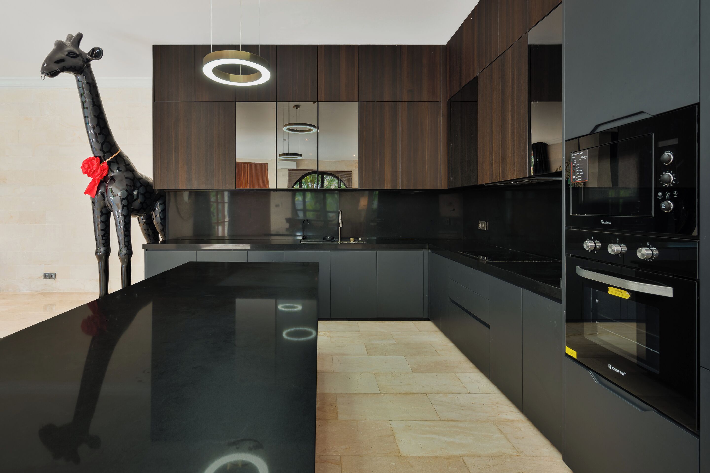 A modern kitchen with a black countertop, built-in oven, and a unique giraffe decoration.