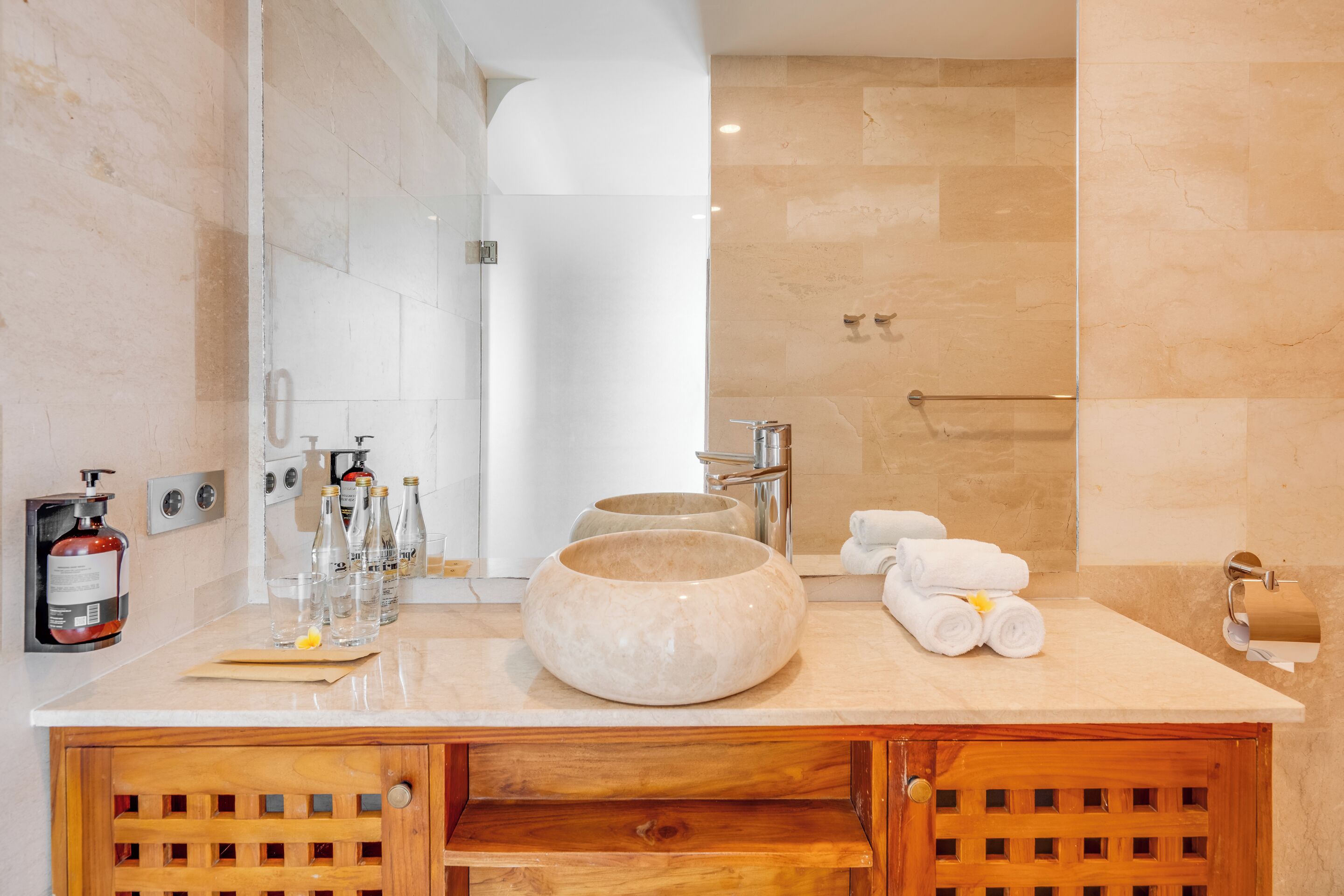 Une salle de bain moderne avec un grand miroir, un lavabo rond en marbre et une cabine de douche en verre.