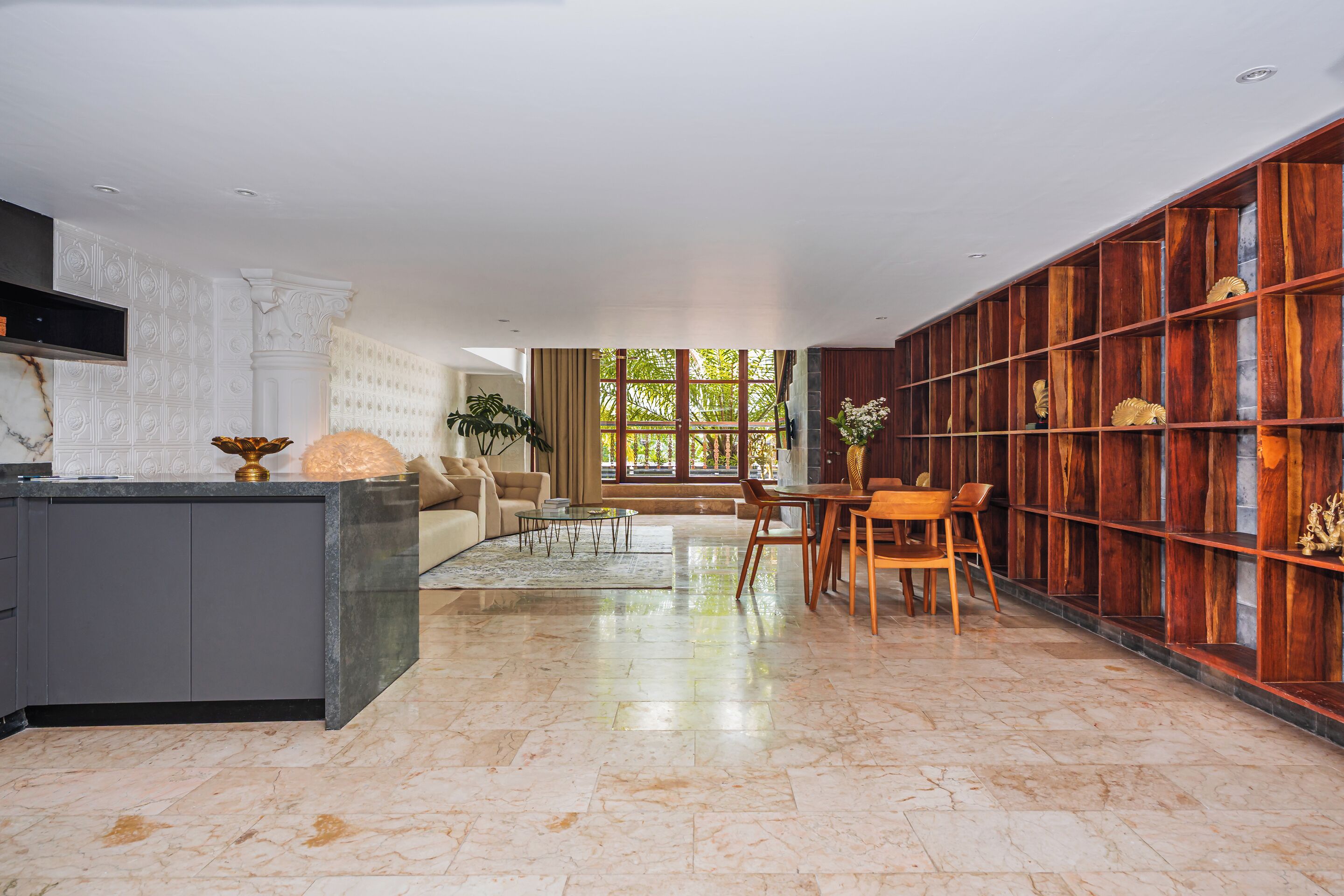 A modern kitchen with a marble countertop, a built-in oven, and a dining area with a wooden table and chairs.