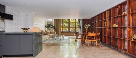 A modern kitchen with a marble countertop, a built-in oven, and a dining area with a wooden table and chairs.