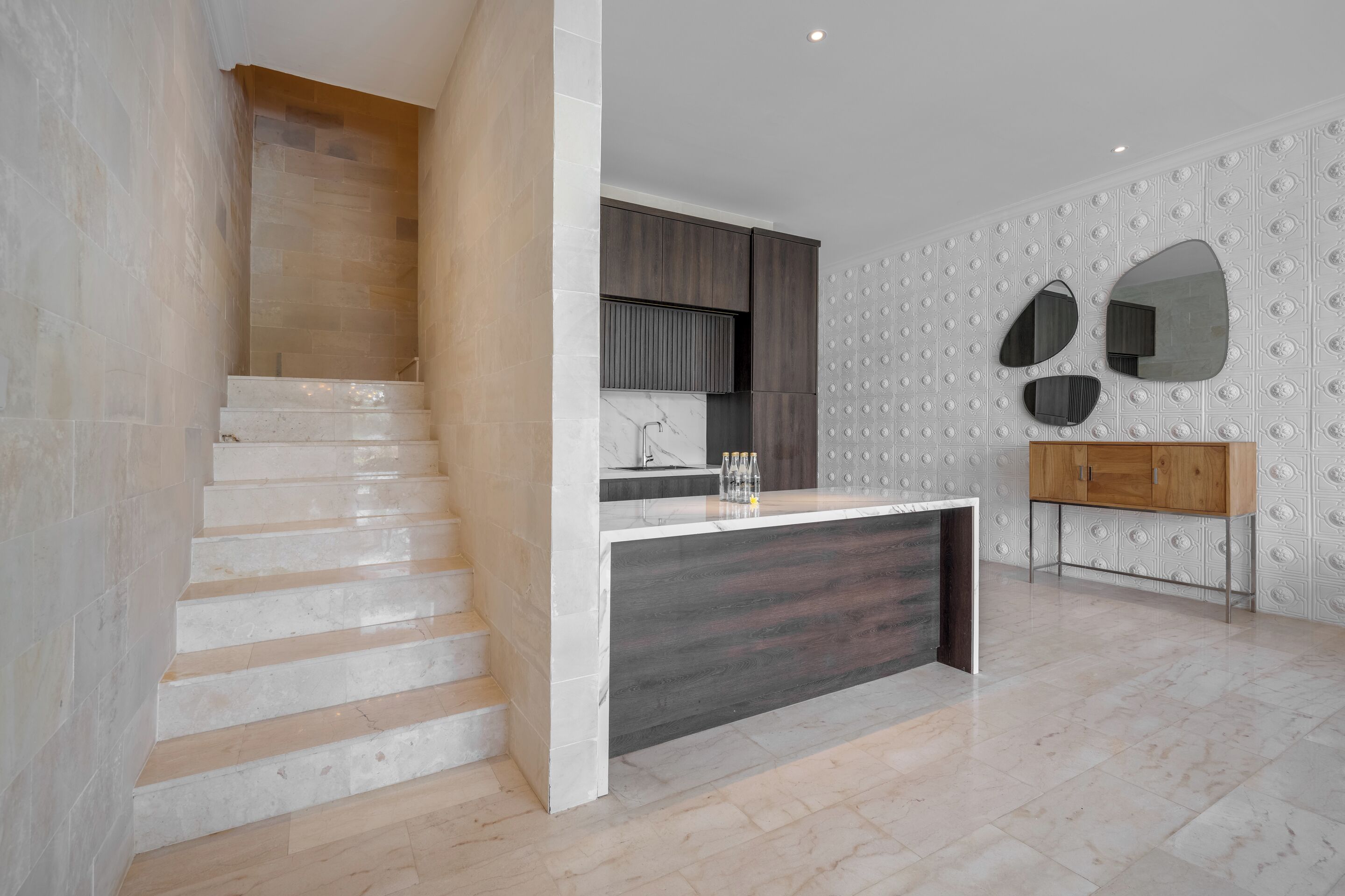 Cocina moderna con escalera de mármol, un armario de madera y salpicadero de azulejos blancos.