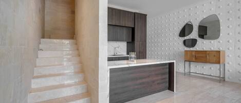 Cocina moderna con escalera de mármol, un armario de madera y salpicadero de azulejos blancos.