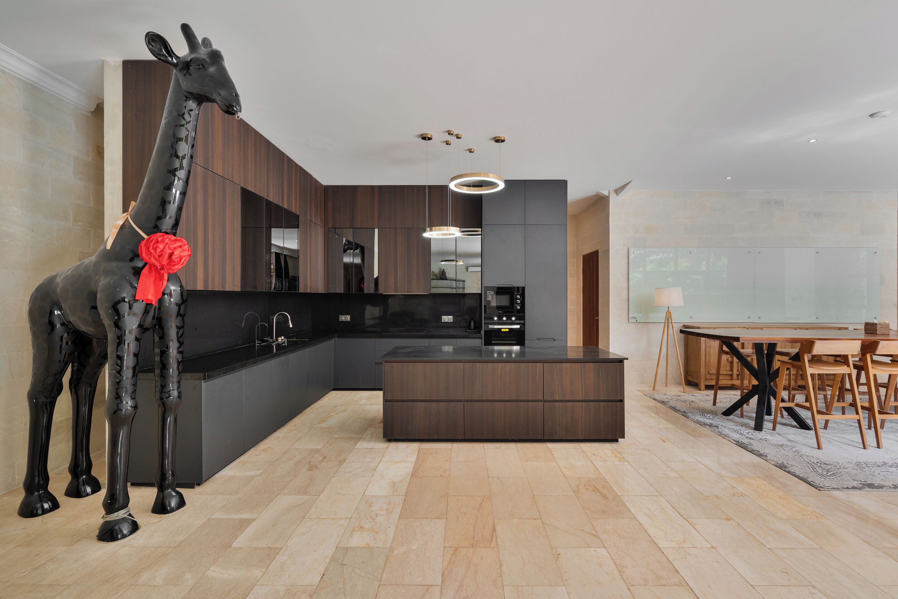 A modern kitchen with dark cabinetry, a central island, and a dining area with a table and chairs.
