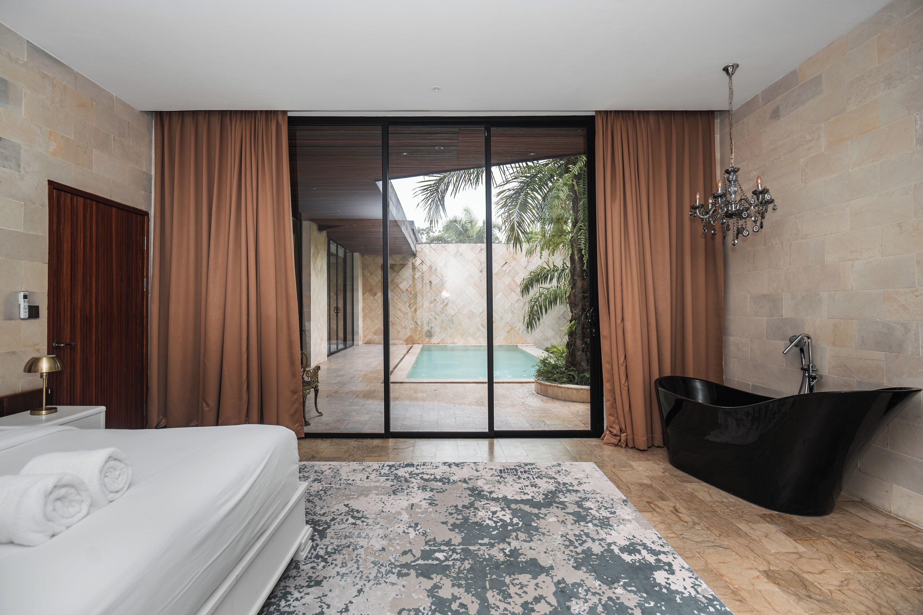 A modern hotel room with a large bed, a bathtub, and a view of an outdoor swimming pool.